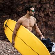 Surfer wearing the Bolle Frank. Model wearing the Bolle Frank 12554 sunglasses, a Matt Black frame with Brown Emerald lenses